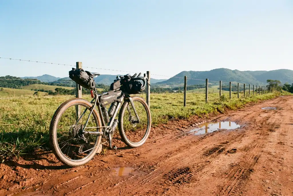 Bicicleta gravel de pneus largos parada em estrada rural de terra vermelha
