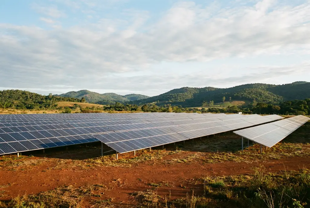 Fileiras de painéis solares instalados no solo, em terreno de área rural